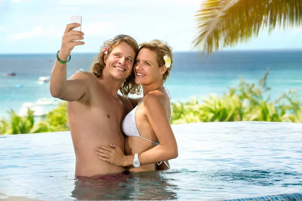 Casal feliz tomando selfie em resort tropical — Fotografia de Stock