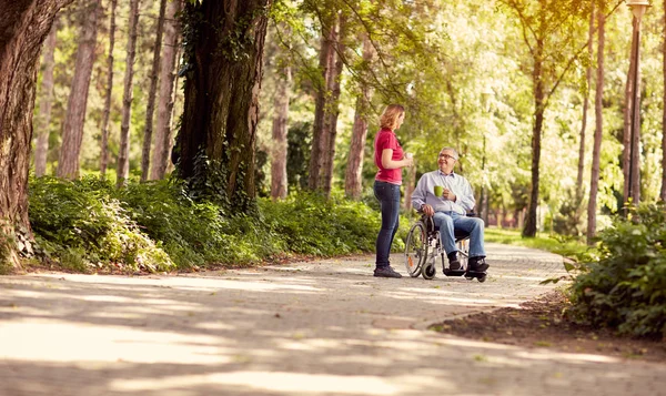 Mujer con su padre feliz discapacitado en silla de ruedas disfrutando del tiempo — Foto de Stock