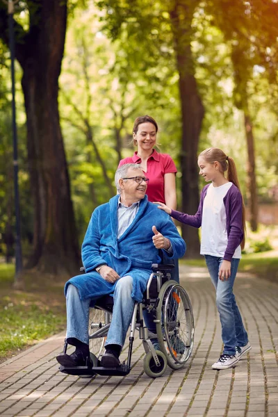 Vrolijke dochter en kleinkinderen een bezoek uitgeschakeld vader in park — Stockfoto