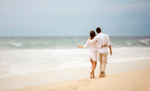 Обнимающая пара, идущая вдоль пляжа — стоковое фото