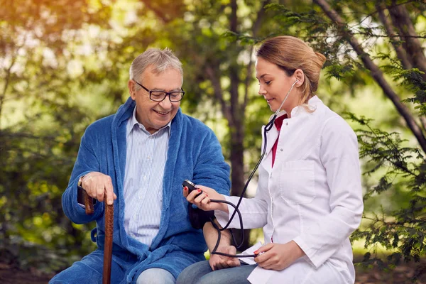 Enfermera evaluación de la presión arterial anciano sonriente hombre — Foto de Stock