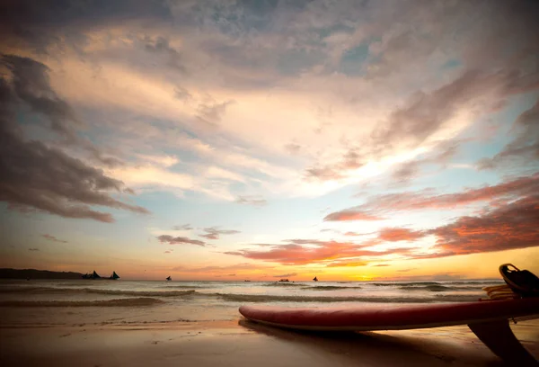 Deska surfingowa na brzegu o zachodzie słońca — Zdjęcie stockowe