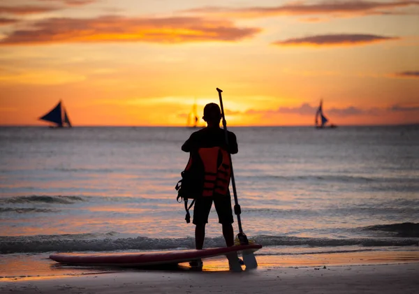 Серфер, стоящий рядом с доской для серфинга — стоковое фото