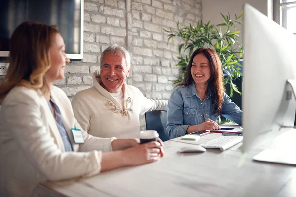 Lächelnde Geschäftsleute, die gemeinsam am Schreibtisch am Computer arbeiten — Stockfoto