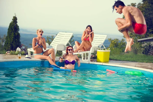 Chicas en la piscina asustadas por su amigo masculino mientras saltan en la piscina —  Fotos de Stock