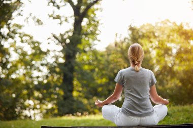 Kadın parkta yoga yapıyor.