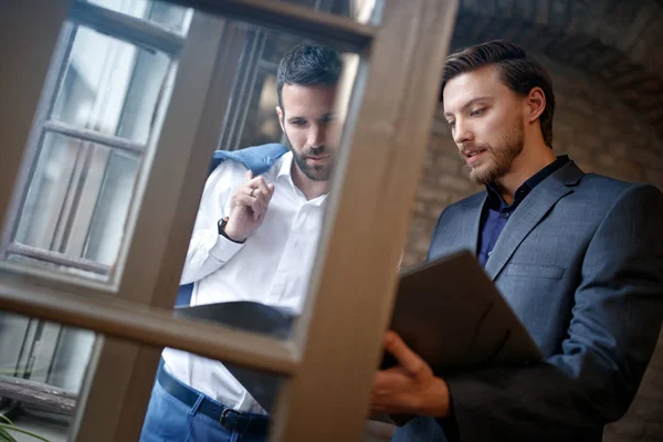 Два молодых бизнесмена в офисе читают бизнес-план — стоковое фото