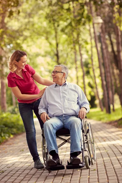 Giovane donna con il padre sorridente disabile in sedia a rotelle — Foto Stock