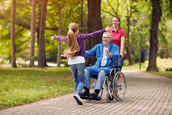 Vrolijke handicap grootvader in rolstoel zijn kleindochter verwelkomen — Stockfoto