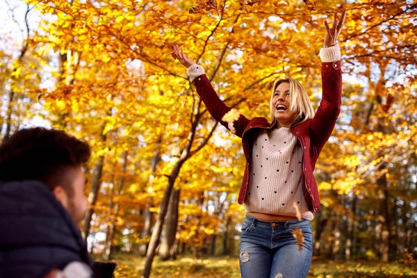 happy woman throwing fall leave
