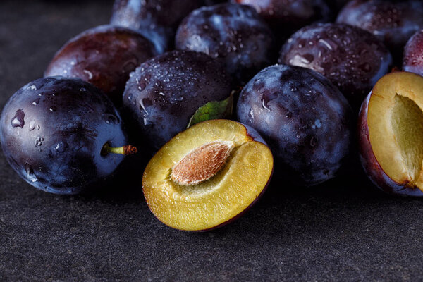 Plums and plums slices close up on dark background