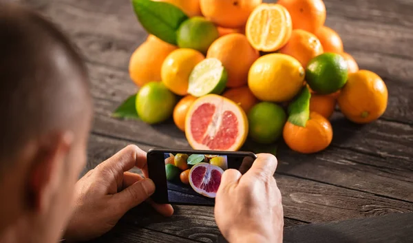 ahşap kağıt üzerinde meyve portakal karşı cep telefonu kullanan adam