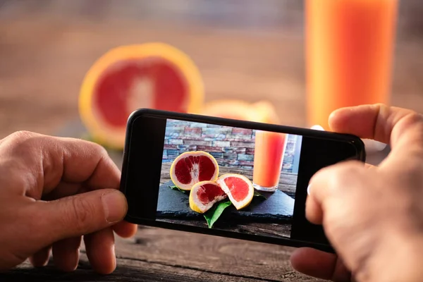 Telefon komórkowy z owoców pomarańczy na podłoże drewniane — Zdjęcie stockowe
