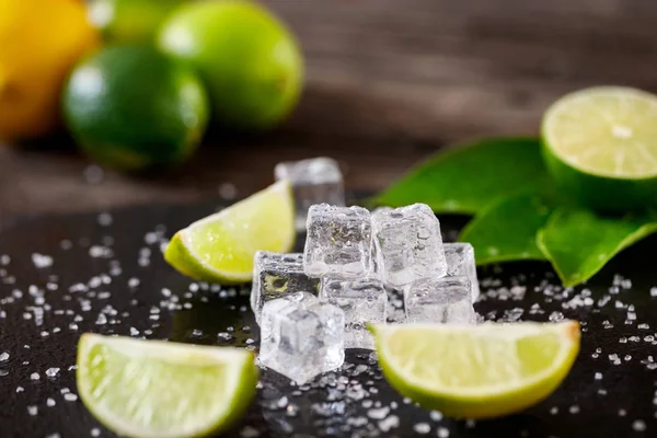 Cubetto di ghiaccio e fetta di lime sul tavolo nero — Foto Stock