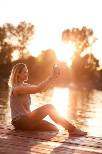 Selfie na doku, w pobliżu rzeki o zachodzie słońca — Zdjęcie stockowe