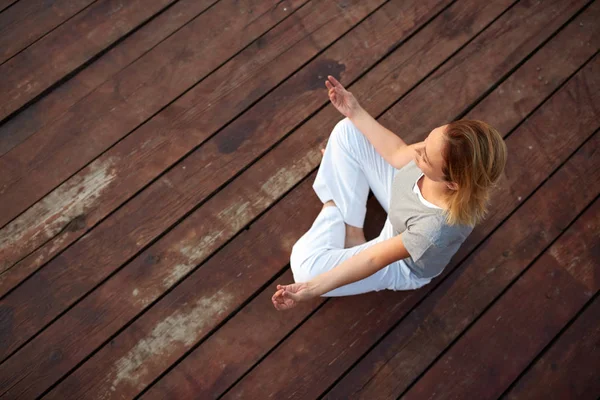 Woman doing yoga on rivers dock — Stock Photo, Image