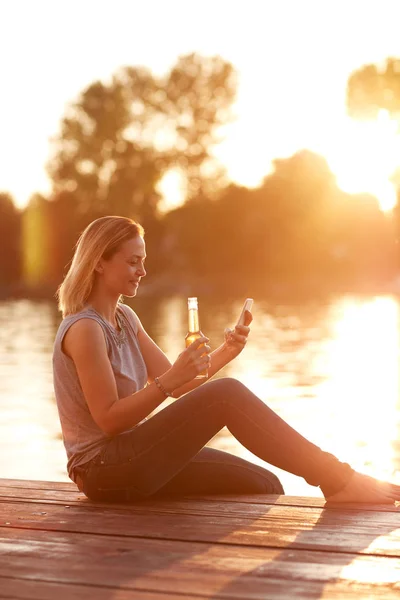 휴대 전화 강 선착장에서 앉아와 여성 — 스톡 사진