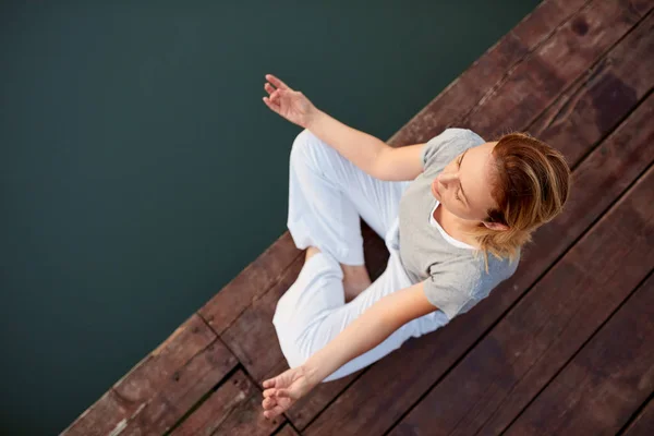 Flicka i yoga position nära vatten — Stockfoto