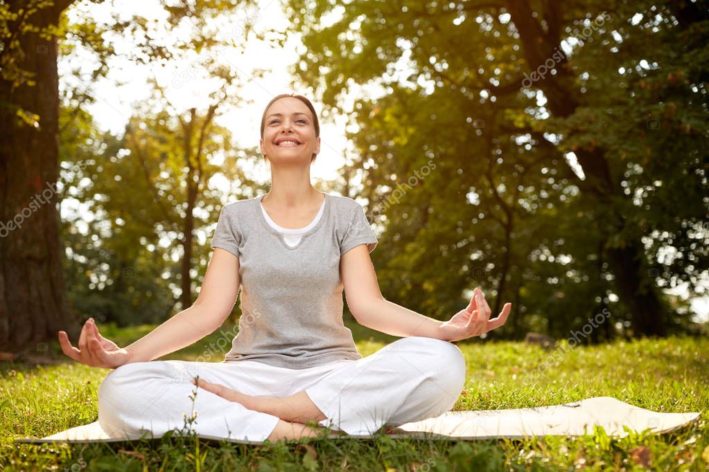 Woman in lotus pose meditate in green park