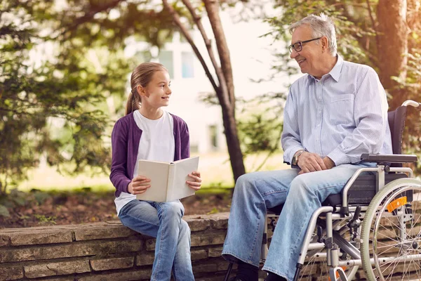 Niepełnosprawnych dziadka w parku spędzać czas razem z jego wnuczka — Zdjęcie stockowe
