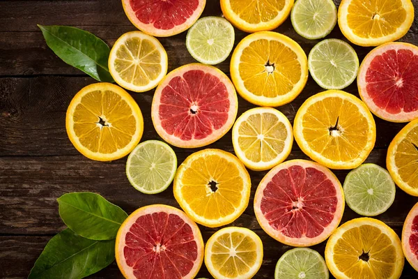Appelsiner, limefrugter, grapefrugter og citroner. Over træbord baggrund - Stock-foto