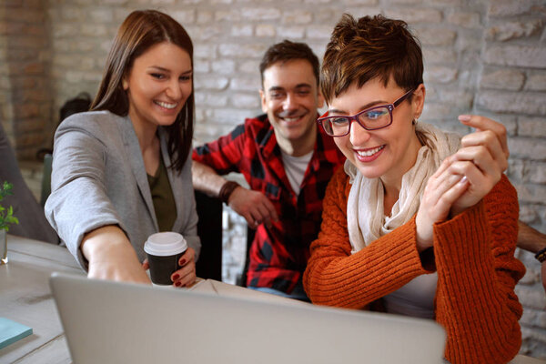 Workers in group looking at laptop