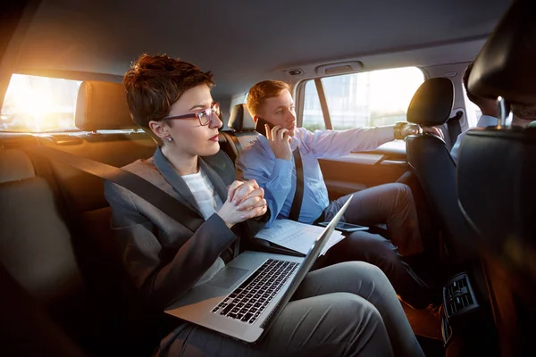 Успешные бизнесмены, работающие вместе на заднем сиденье автомобиля — стоковое фото