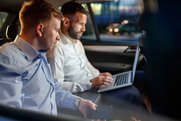 Empresarios trabajan en la noche en el asiento trasero del coche —  Fotos de Stock