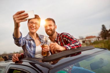 günbatımı ve almak bir selfie sırasında smartphone ile oturan arkadaşlar