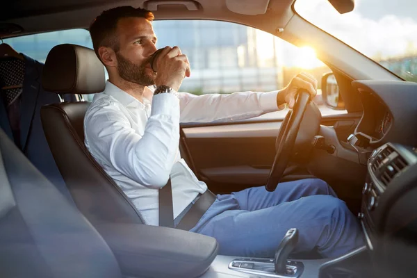 Homem de negócios dirigindo carro enquanto bebe uma xícara de café — Fotografia de Stock