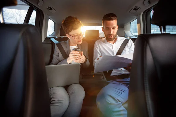 Glad affärskollegor arbetar med dator i bilen — Stockfoto