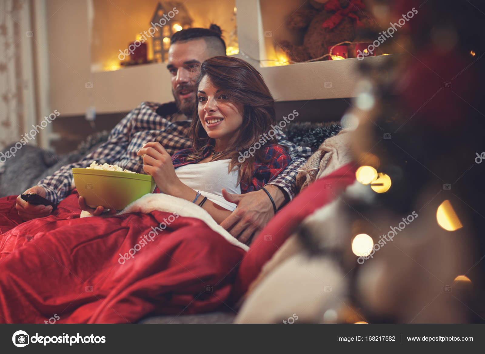 Мужчина и женщина в постели смотрят телевизор и едят поп