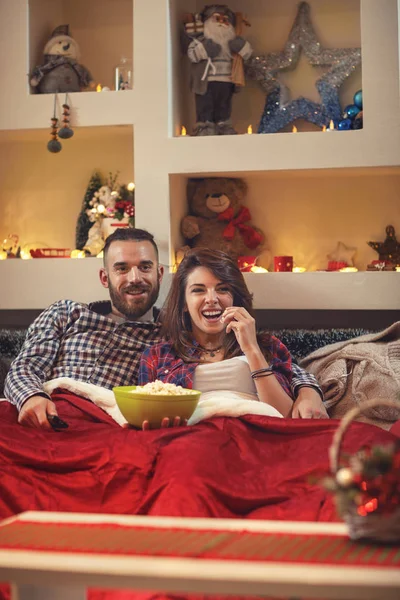 Młoda para w łóżku jeść popcorn podczas oglądania telewizji — Zdjęcie stockowe