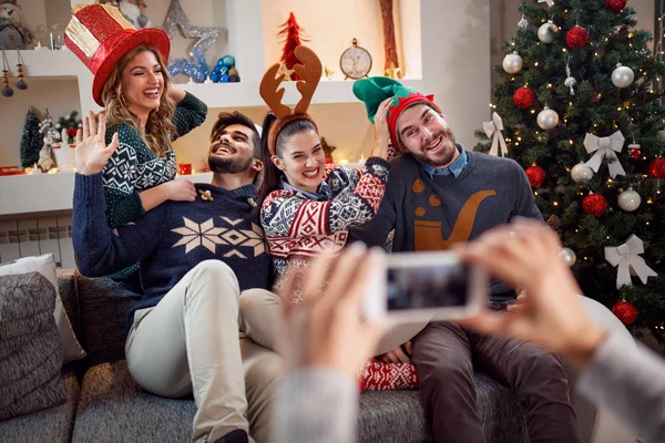 Amigos felizes tirar fotos de Natal em um telefone — Fotografia de Stock