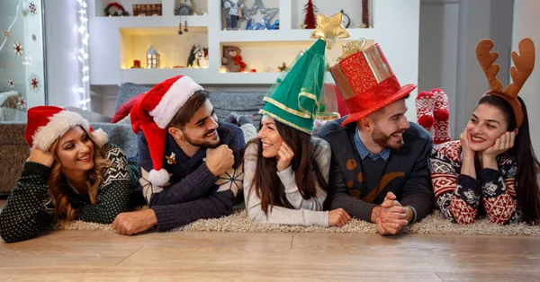Друзі з різдвяними капелюхами насолоджуються разом — стокове фото