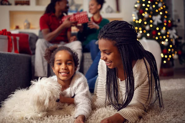 Lachende zusters zijn spelen met de hond, die ze liggen op verdieping — Stockfoto