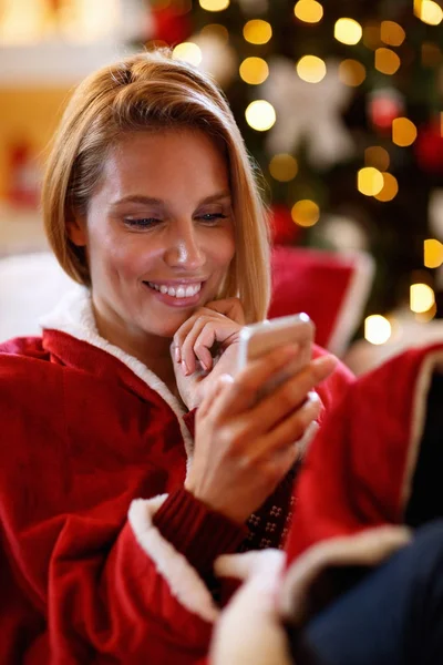 Glückliche Frau tippt eine Nachricht und entspannt über Weihnachten — Stockfoto