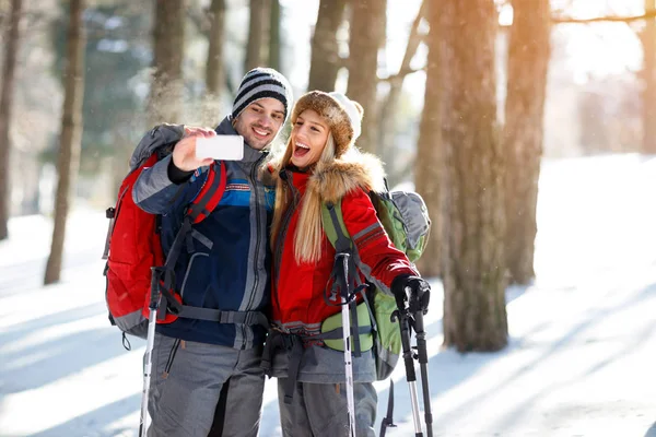 Erkek ve dişi yürüyüşçü kışın ahşap fotoğraf çekmek 