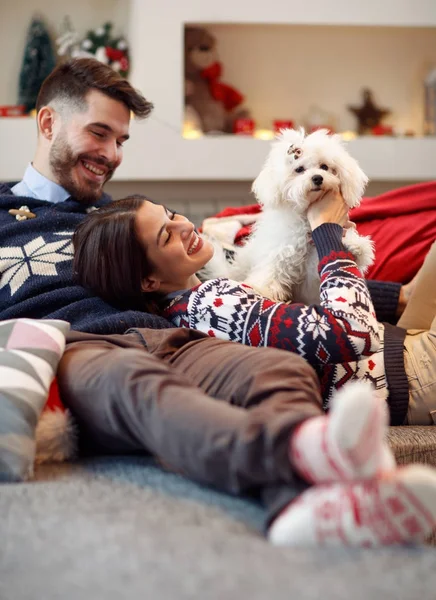 Weihnachtszeit - Paar entspannt zu Hause und spielt mit Hund — Stockfoto