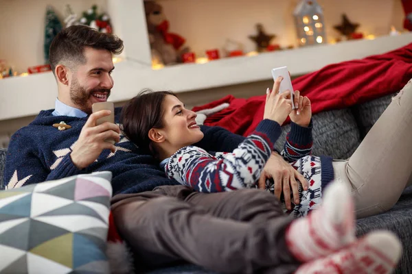 Paar an Heiligabend umarmt Liegende und schaut aufs Handy — Stockfoto