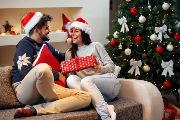 Feliz pareja en el sombrero de Santa con regalo de Navidad —  Fotos de Stock