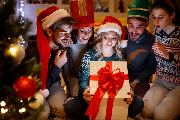 Smiling friends opening magic Christmas gift — Stock Photo, Image