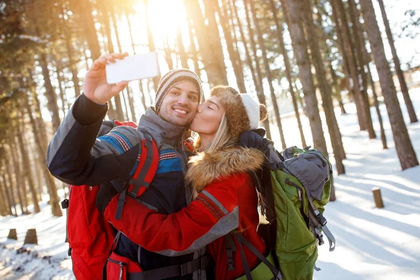 Chica beso su novio en snowy bosque —  Fotos de Stock