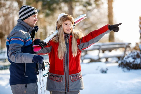 Chica en el esquí muestra algo a su pareja —  Fotos de Stock