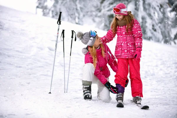 Mère fixant pantalon à fille sur le terrain de ski — Photo