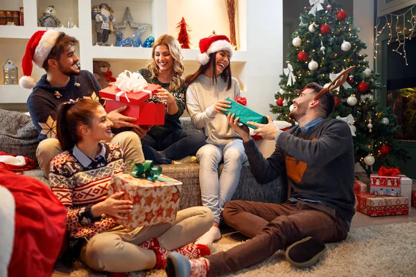 Щасливі друзі сміються і діляться різдвяним подарунком — стокове фото