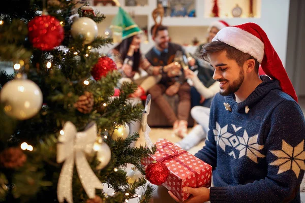 Щаслива людина в Санта Клауса капелюх з різдвяні подарунки на дому — стокове фото