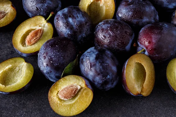 Primer plano de ciruelas y ciruelas rebanadas sobre fondo oscuro — Foto de Stock