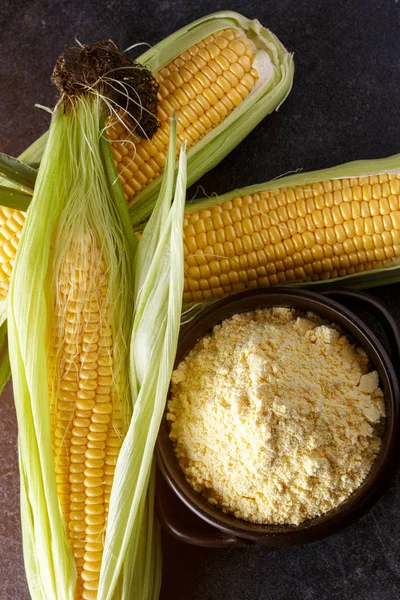 Fresh Corn and corn grits in bowl on black table