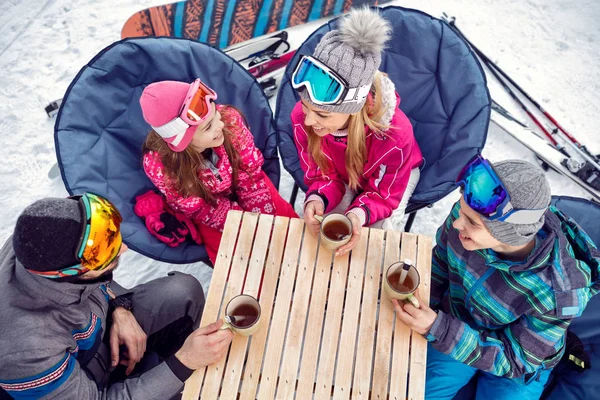 Family enjoying on hot drink at ski resort — Stock Photo, Image